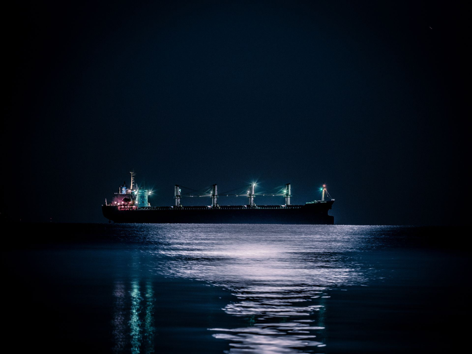 Bulk carrier anchored at sea under a night sky