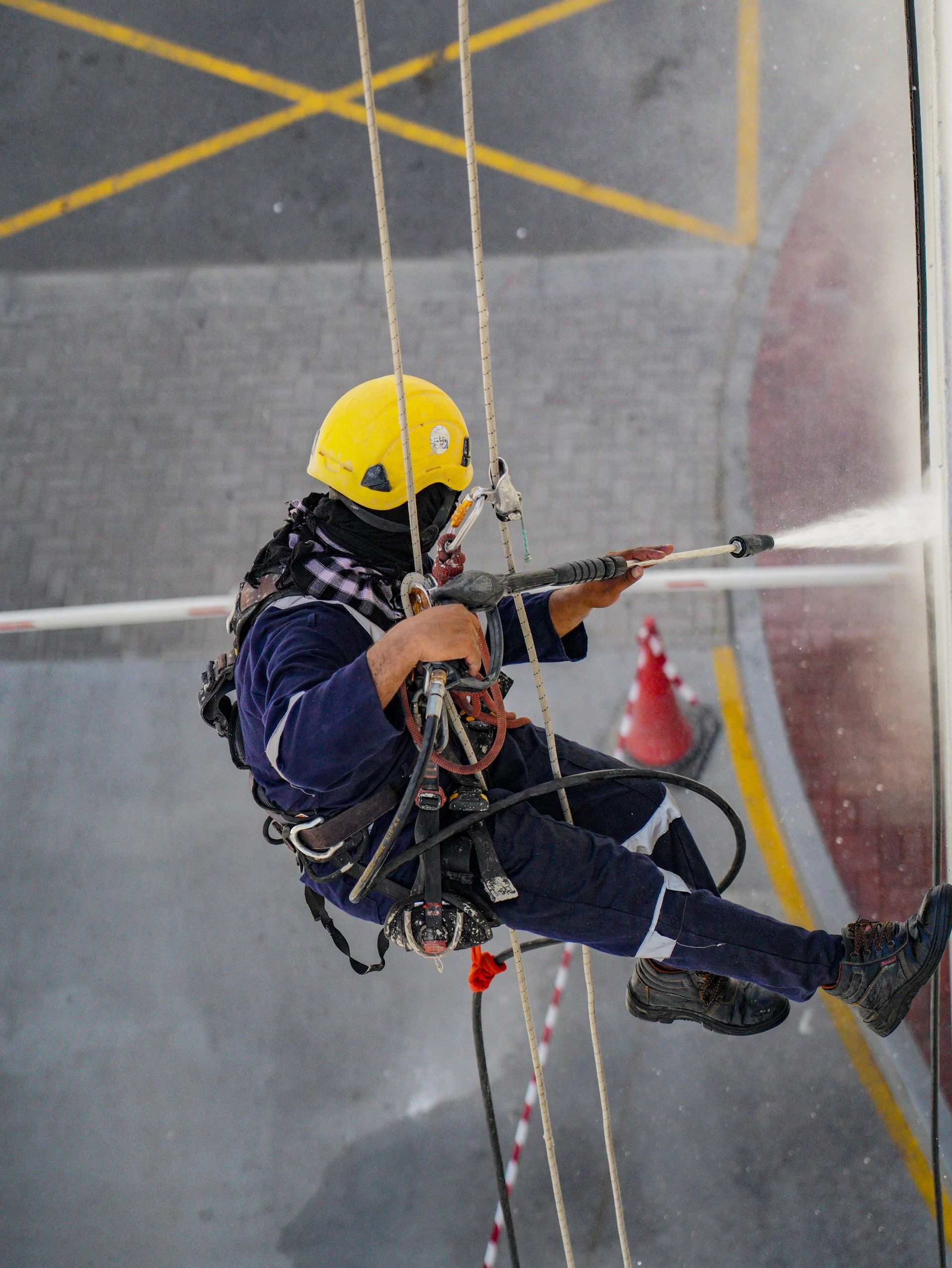 Rope-access technician pressure washing an industrial structure