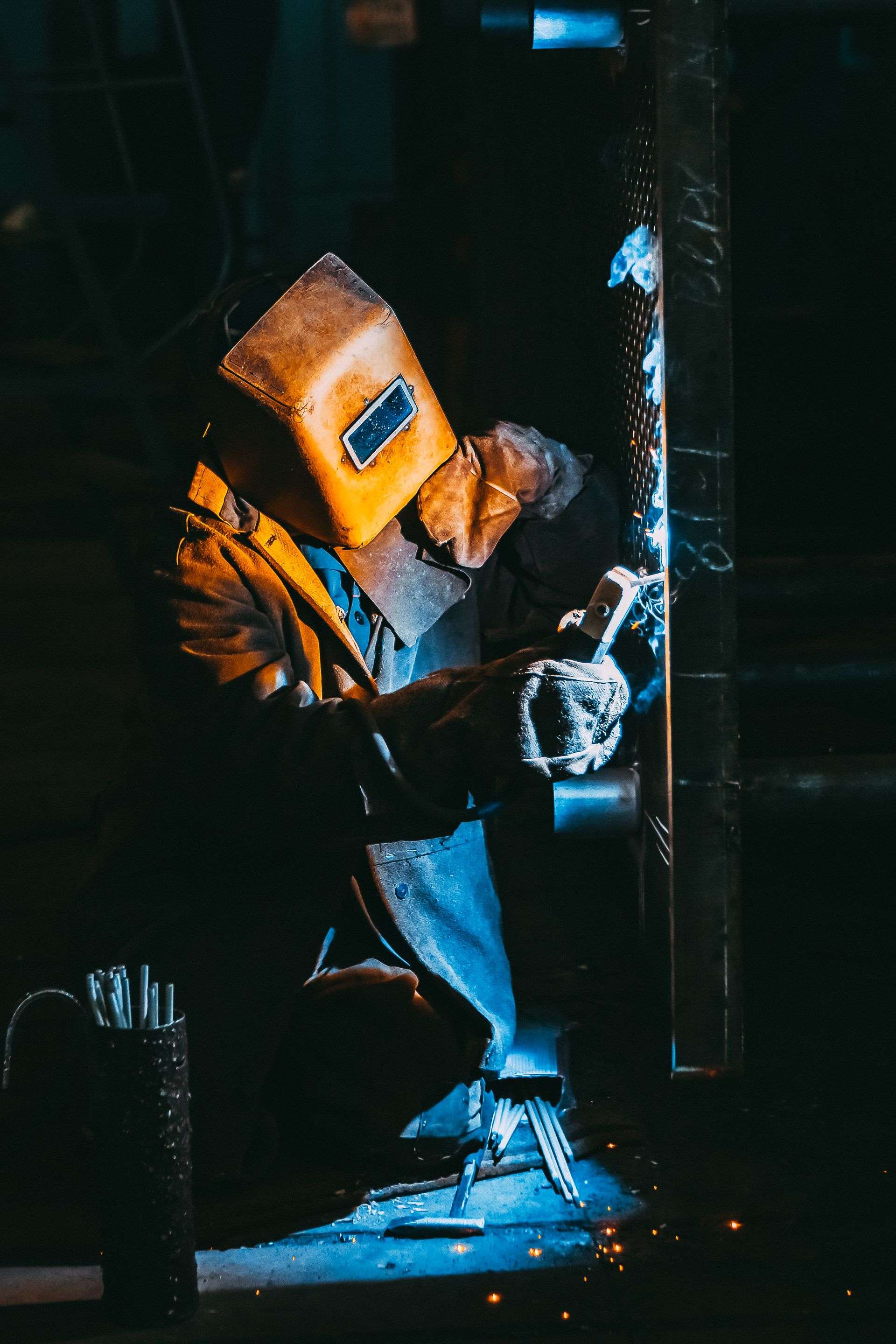 Welder at work in a dark fabrication workshop